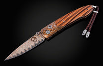 William Henry knife with zebra wood handle and damascus steel blade on a black background