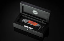 Folding knife with wooden blade in a black display box on a dark background