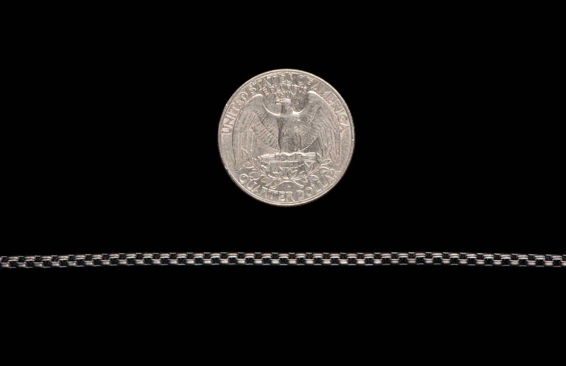 Black Box Chain men's jewelry from William Henry is bronze with black PVD coating for easy care and durability. Image shows the Black Box Chain next to a Quarter as a size reference. 