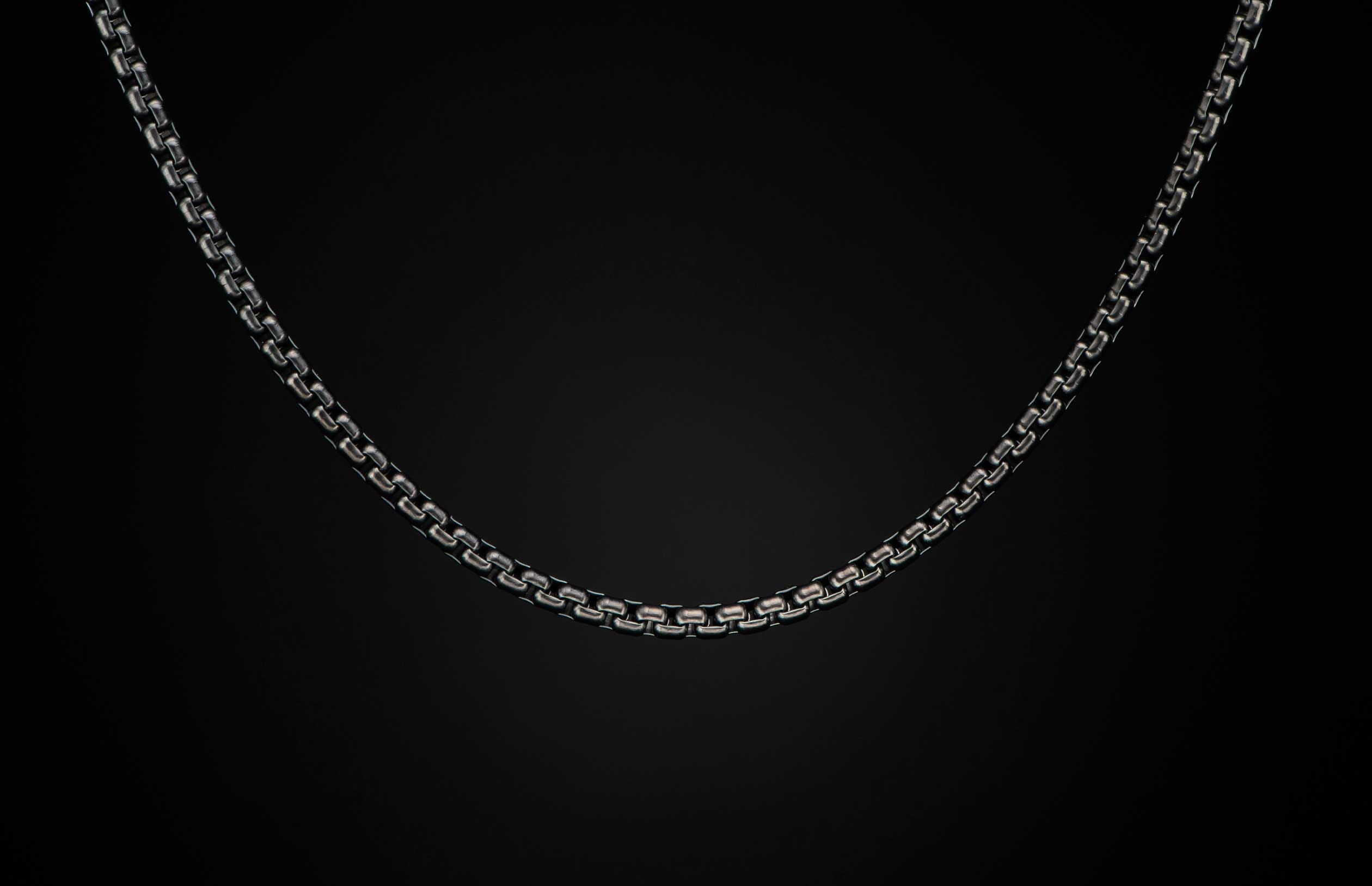 Black Box Chain men's jewelry from William Henry is bronze with black PVD coating for easy care and durability. The chain is displayed on a black background.