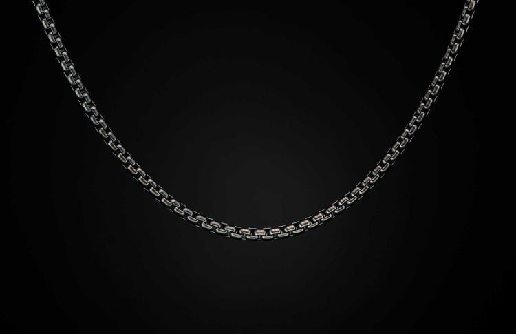 Black Box Chain men's jewelry from William Henry is bronze with black PVD coating for easy care and durability. The chain is displayed on a black background.