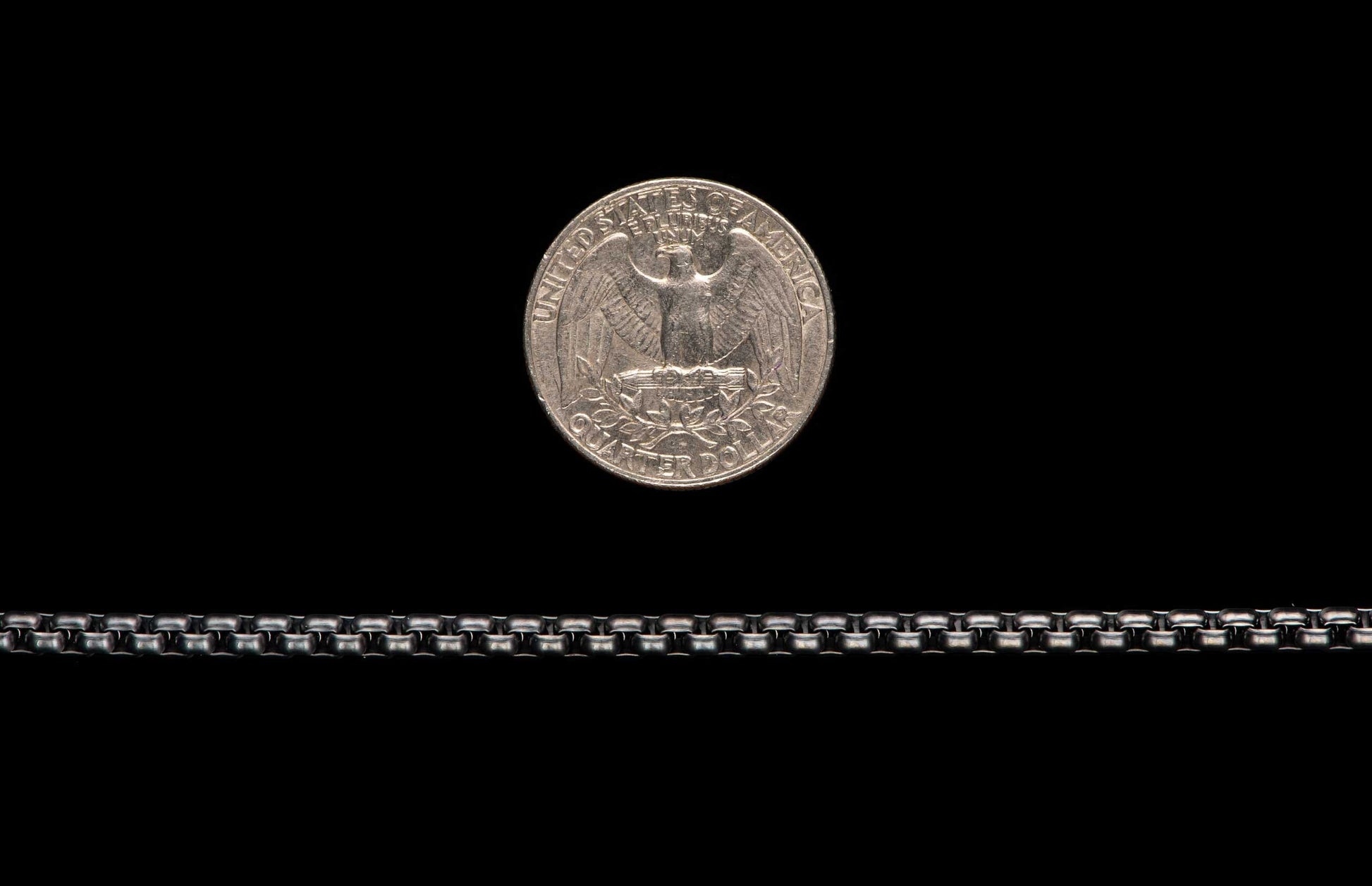 Black Box Chain men's jewelry from William Henry is bronze with black PVD coating for easy care and durability. Image shows the Black Box Chain next to a U.S. quarter as a size reference.