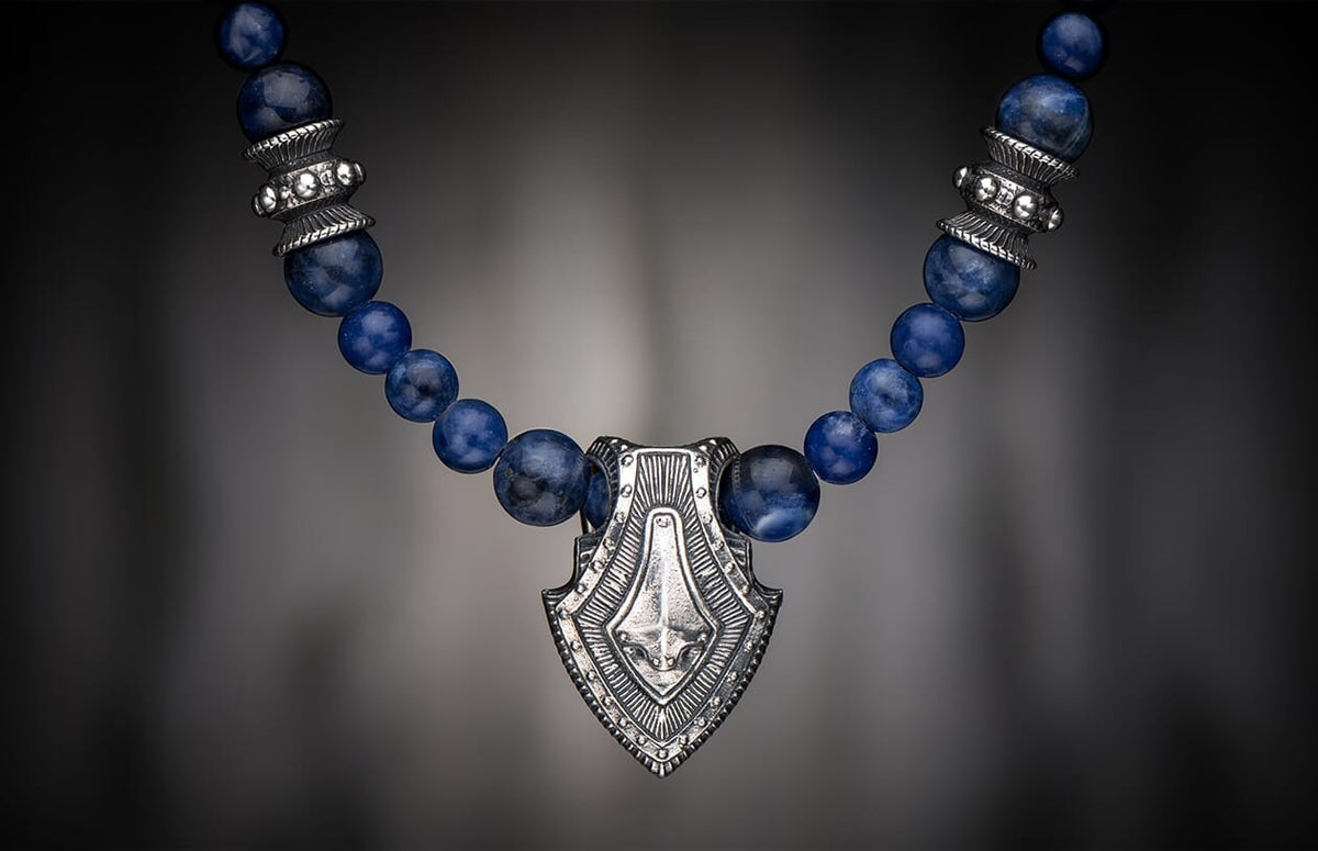Sodalite Shield necklace with an ornate silver-toned pendant and round blue sodalite beads.