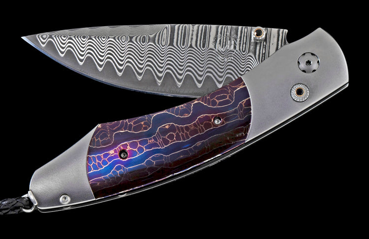 Folding knife with a wavy Damascus steel blade, iridescent purple and blue handle featuring an organic network pattern, and brushed metal bolsters.