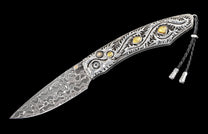 A decorative knife with a Damascus steel blade and an intricately engraved silver handle featuring yellow stone inlays, a black braided lanyard.
