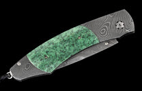 Folding knife with dark Damascus pattern handle, green speckled insert, and lanyard loop.