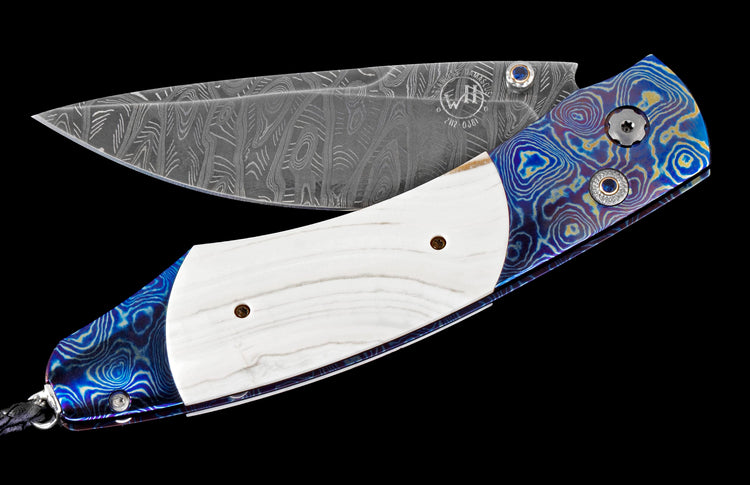 Folding knife with a patterned Damascus blade and a handle featuring white inlay and vibrant blue and gold swirled sections.