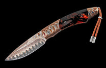 Custom folding knife with a wavy Damascus steel blade, multi-material handle with orange gems, and a braided leather lanyard.
