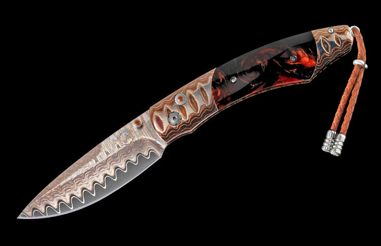 Custom folding knife with a wavy Damascus steel blade, multi-material handle with orange gems, and a braided leather lanyard.