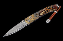 Decorative folding knife with a wavy Damascus blade, gold engraved frame, feather handle scales, and a braided leather lanyard with silver beads.