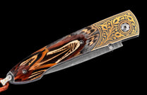 Decorative folding knife featuring a feather inlay handle, gold scrollwork, and a Damascus steel blade, with a brown lanyard.