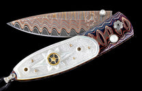 Decorative open folding knife with multi-toned wavy Damascus blade, mother-of-pearl handle with starburst, and swirled scales.