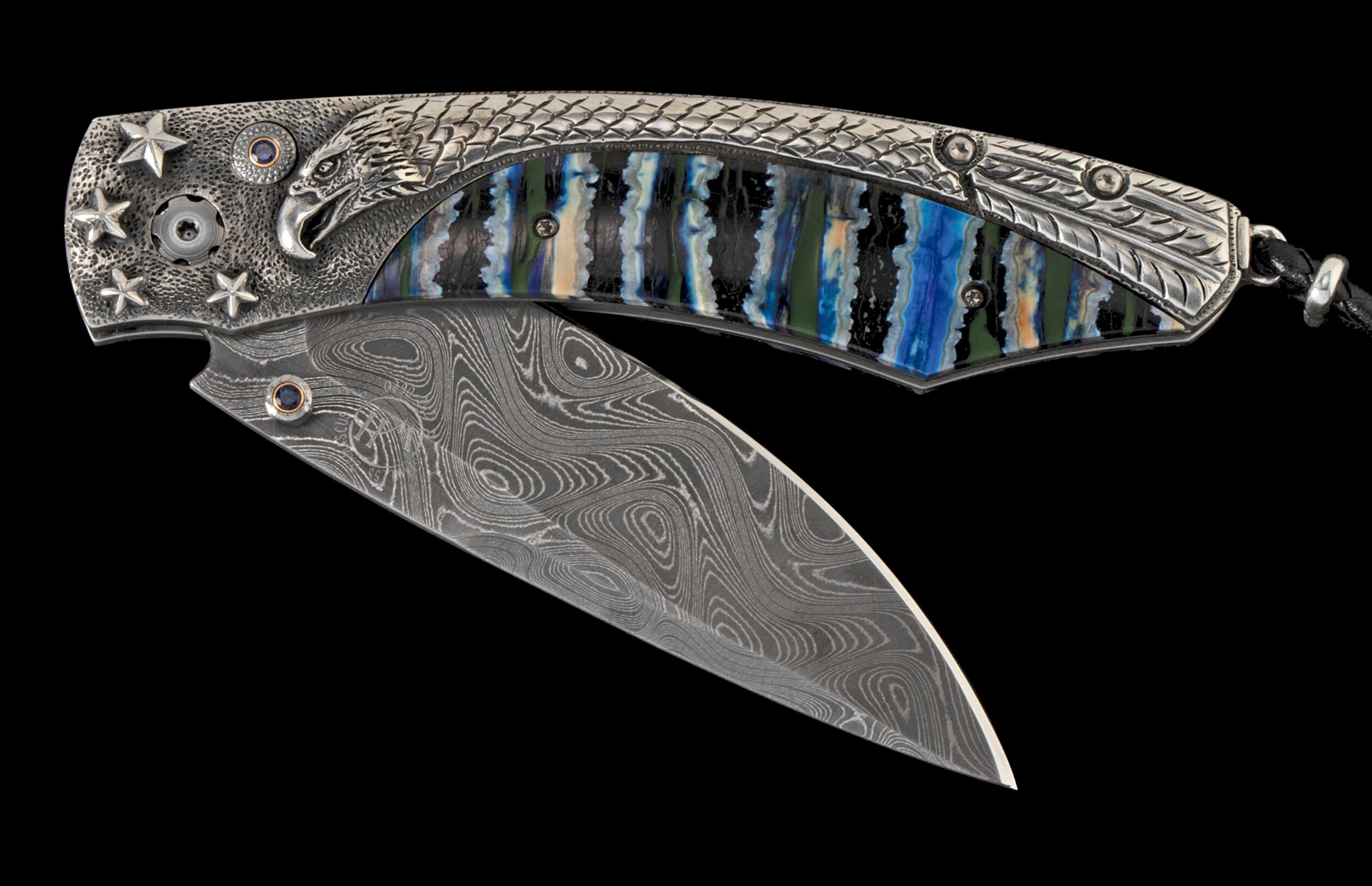 Ornate folding knife with Damascus steel blade and silver handle featuring an eagle head, stars, blue gemstones, and a vibrant striped inlay.