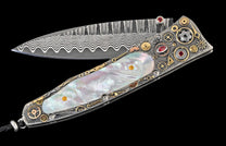 Folding knife with a wavy Damascus steel blade and an ornate handle featuring iridescent mother-of-pearl, gears, and red gemstones.