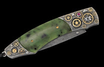 Folding knife with a green jade handle, silver-toned metal featuring gold gears and a ruby, and a Damascus steel blade.