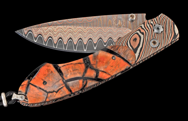 Open folding knife with a wavy copper damascus blade, a striped bolster, and a cracked orange handle.