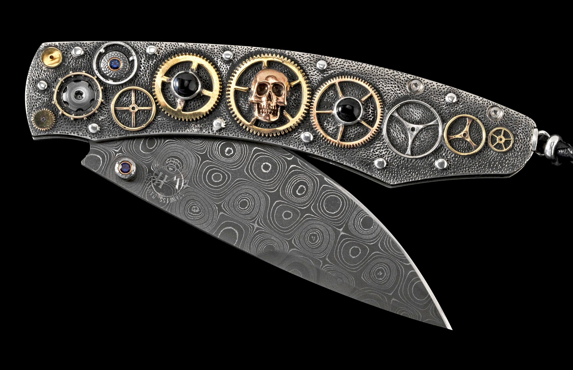 Folding knife with a textured silver-toned handle featuring gold and silver gears, a copper skull, blue and black gems, and a patterned Damascus steel blade.