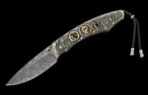 Ornate Damascus knife with a textured metal handle, decorated with gears, a small skull, and a black braided leather lanyard.