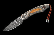 Damascus steel knife with an ornate silver handle featuring a carved feather, mother-of-pearl, and a brown leather lanyard.