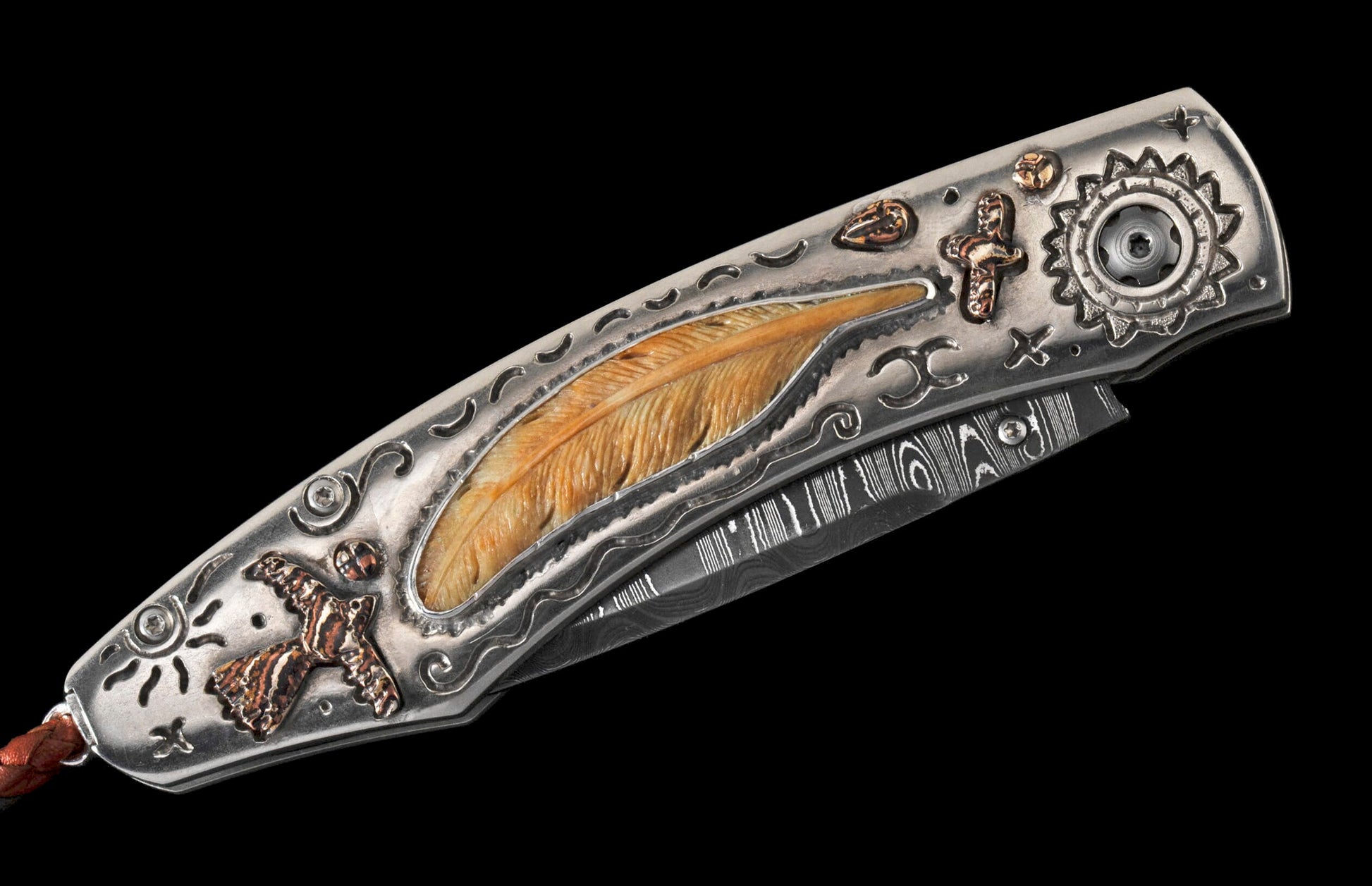 Ornate folding knife with a Damascus blade and silver-toned handle, featuring a carved feather inlay, bird, and cross motifs.