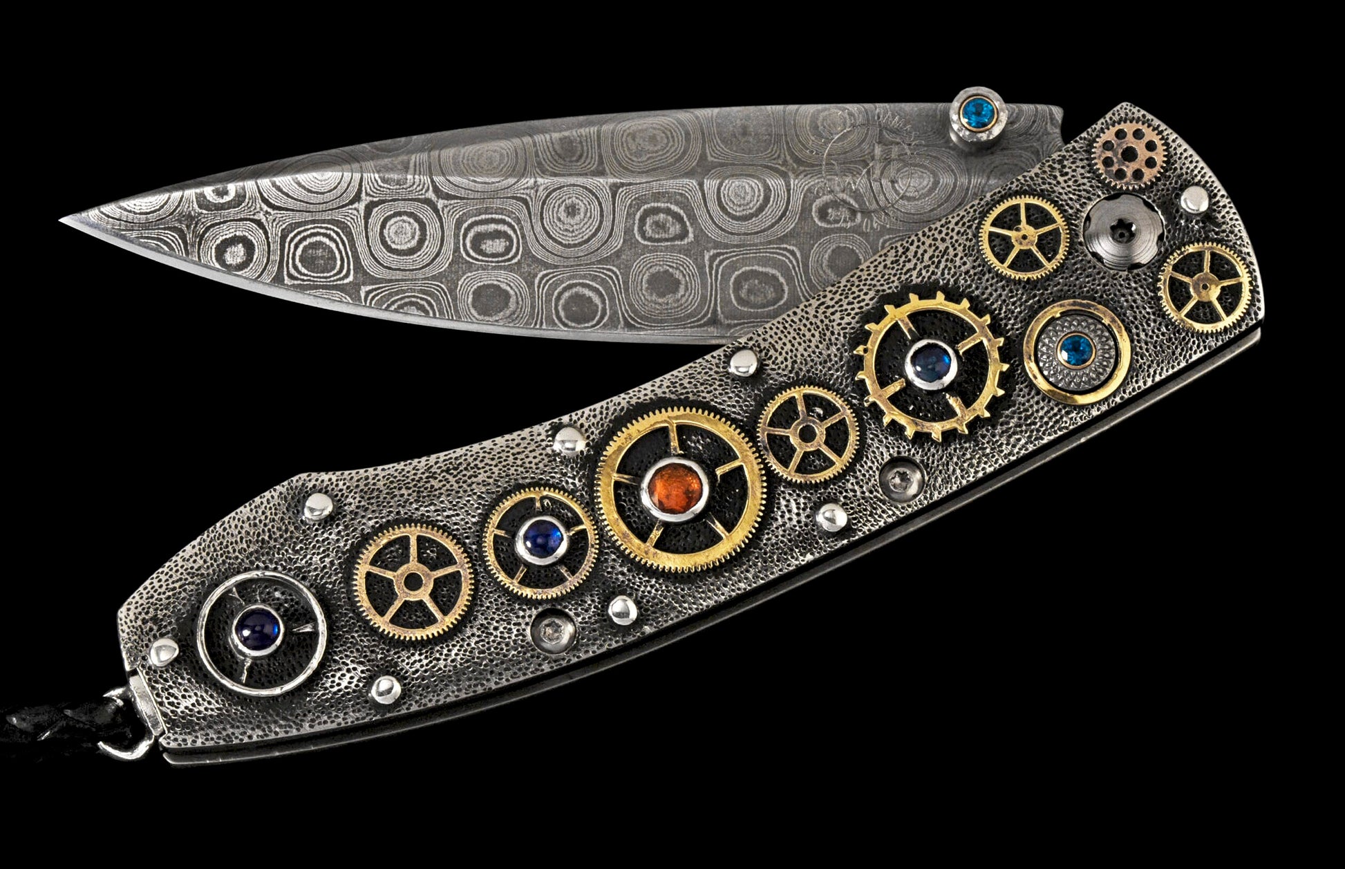 Open folding knife with a patterned Damascus steel blade and a textured handle adorned with golden gears and colorful gemstones.