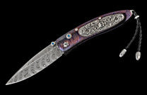 Damascus steel knife with a multi-colored handle featuring blue gems, an ornate skull, and a black leather lanyard.