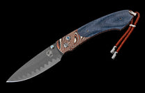 Folding knife with a dark grey blade, blue denim and brown patterned handle, blue gemstone accents, and a braided leather lanyard.