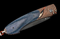 Closed folding knife with a blue denim-textured handle and orange, black, and cream striped pattern, featuring a dark blade and an orange cord lanyard.