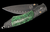 Folding knife with dark gray Copper Damascus blade, WH logo, wavy pattern, green speckled handle scale, and patterned steel frame with orange accents.