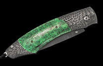 Green speckled handle folding knife with swirling patterned silver metal and a dark blade, attached with a black lanyard.
