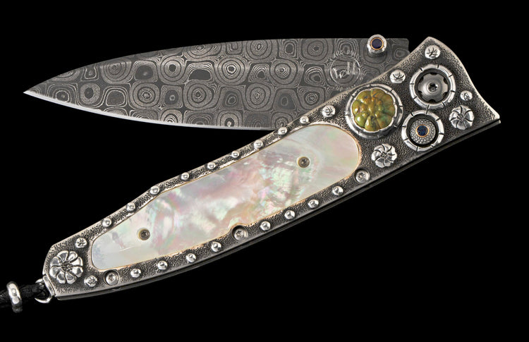 Ornate open folding knife with a swirled Damascus steel blade, iridescent mother-of-pearl handle, sterling silver details, green jasper, and blue sapphires.
