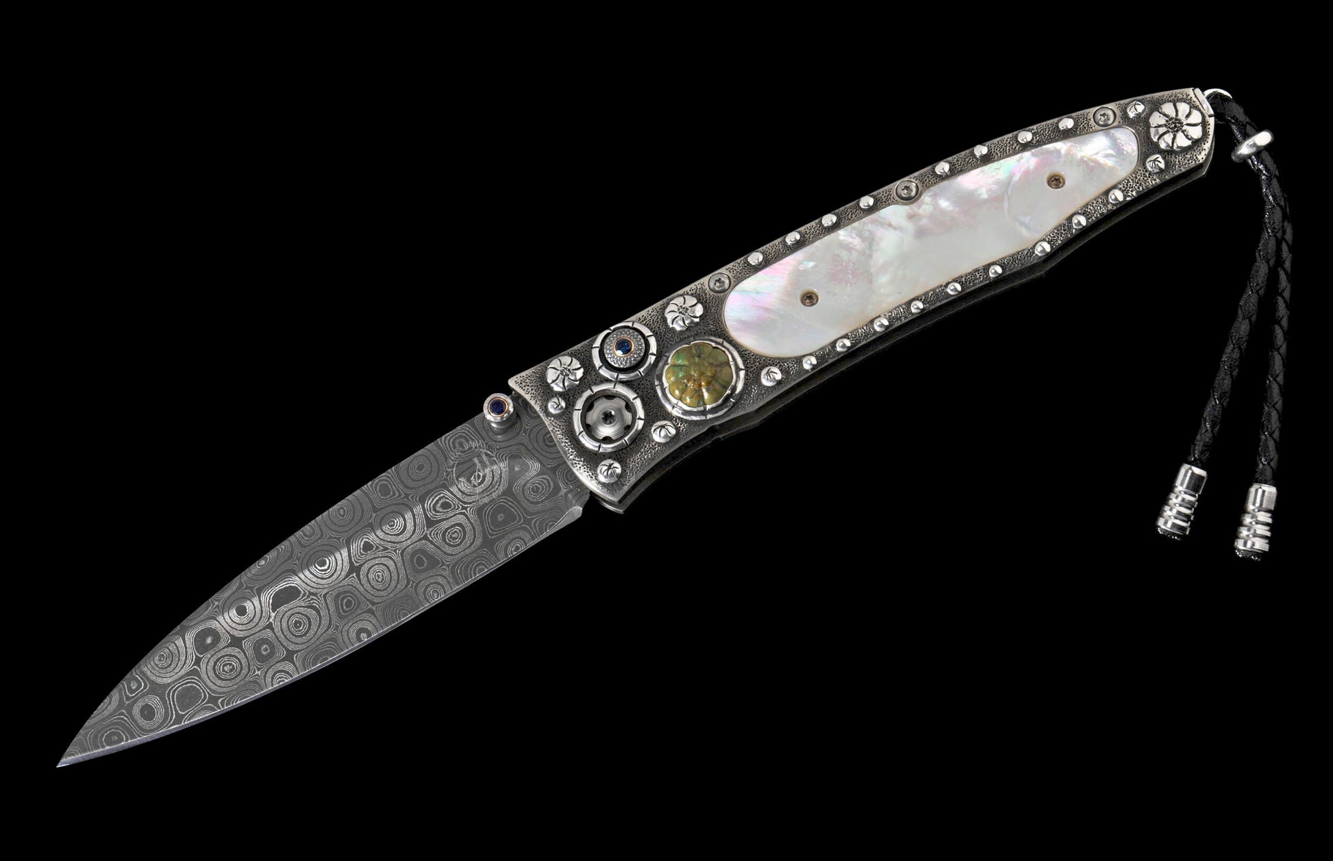 Ornate folding knife with a patterned Damascus blade, iridescent mother-of-pearl handle, studded silver adornments, and a black leather lanyard.