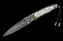 Ornate folding knife with a patterned Damascus blade, iridescent mother-of-pearl handle, studded silver adornments, and a black leather lanyard.