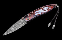 Ornate folding knife with a wavy Damascus steel blade, iridescent handle featuring a white dragon inlay, red accent gems, and a braided lanyard.