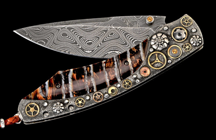 Folding knife with a wavy Damascus steel blade, and a handle featuring striped material and textured metal with watch gears, floral elements, and yellow gems.