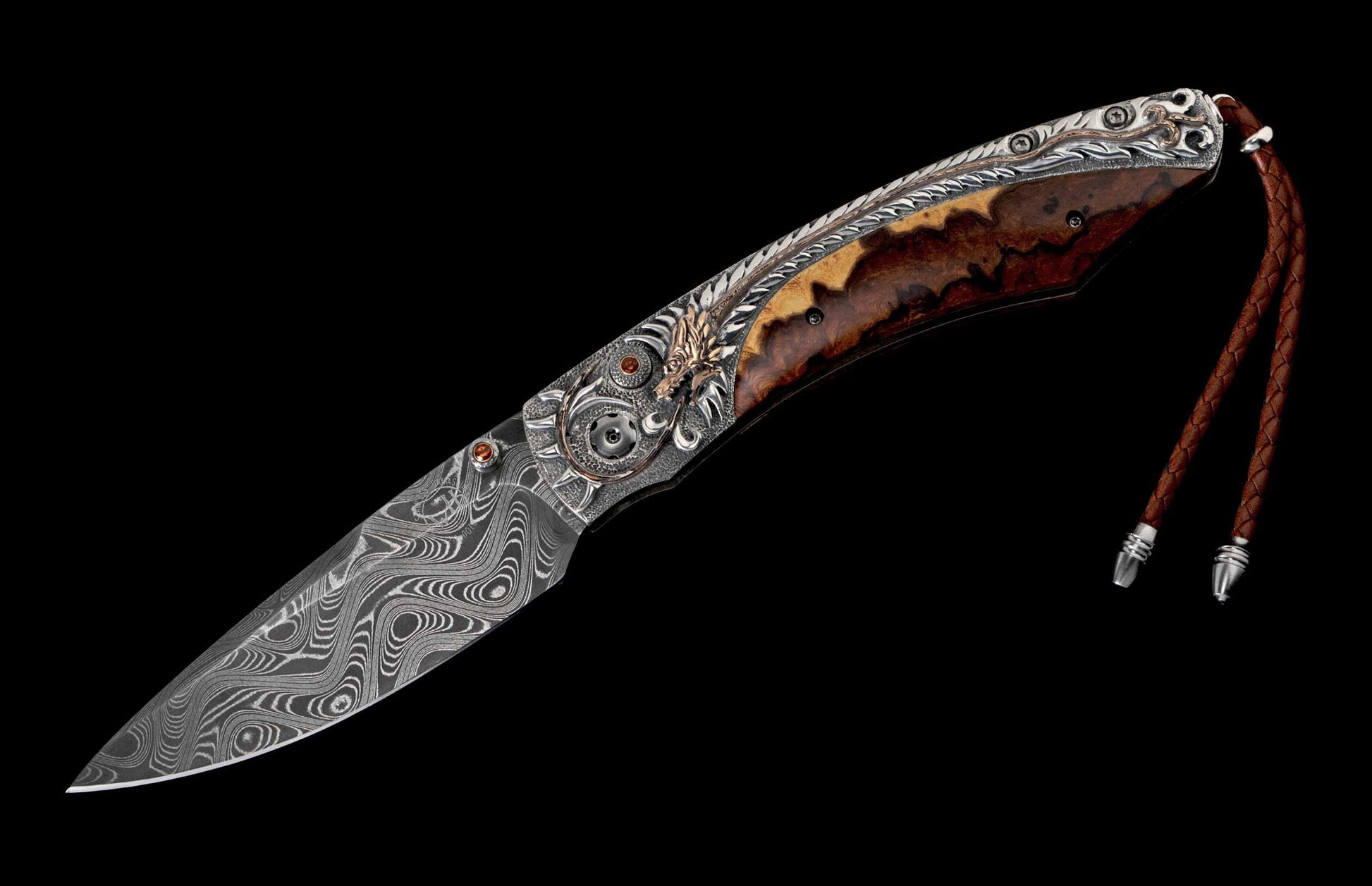 Ornate folding knife with a Damascus steel blade, brown wood handle, silver detailing featuring a golden dragon, and a braided leather lanyard.