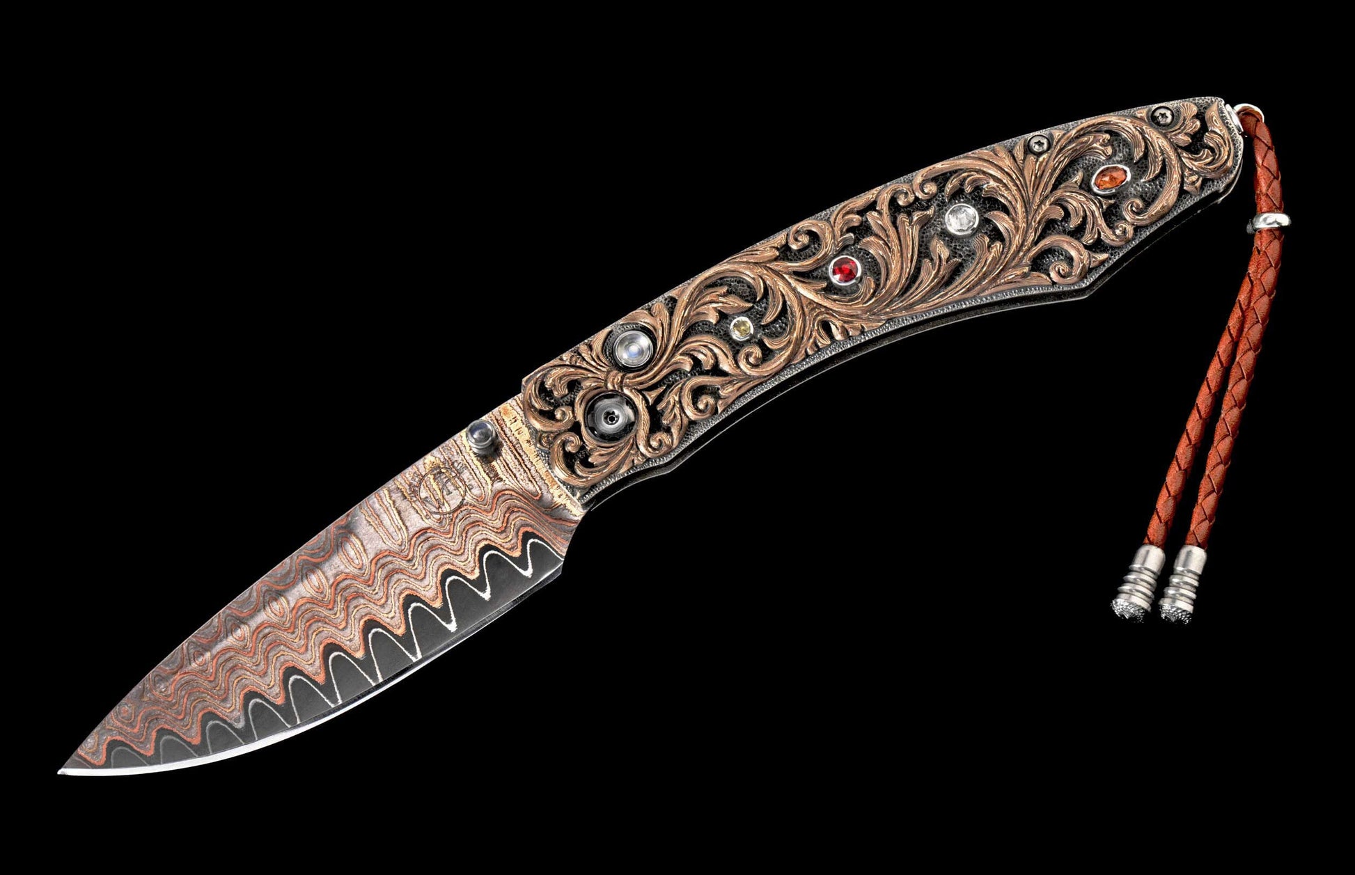 Ornate folding knife with a wavy Damascus steel blade, engraved handle with multi-colored gemstones, and a brown leather lanyard.