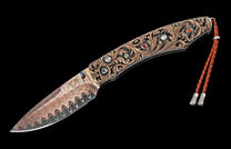 Ornate folding knife with a wavy Damascus steel blade, engraved handle with multi-colored gemstones, and a brown leather lanyard.
