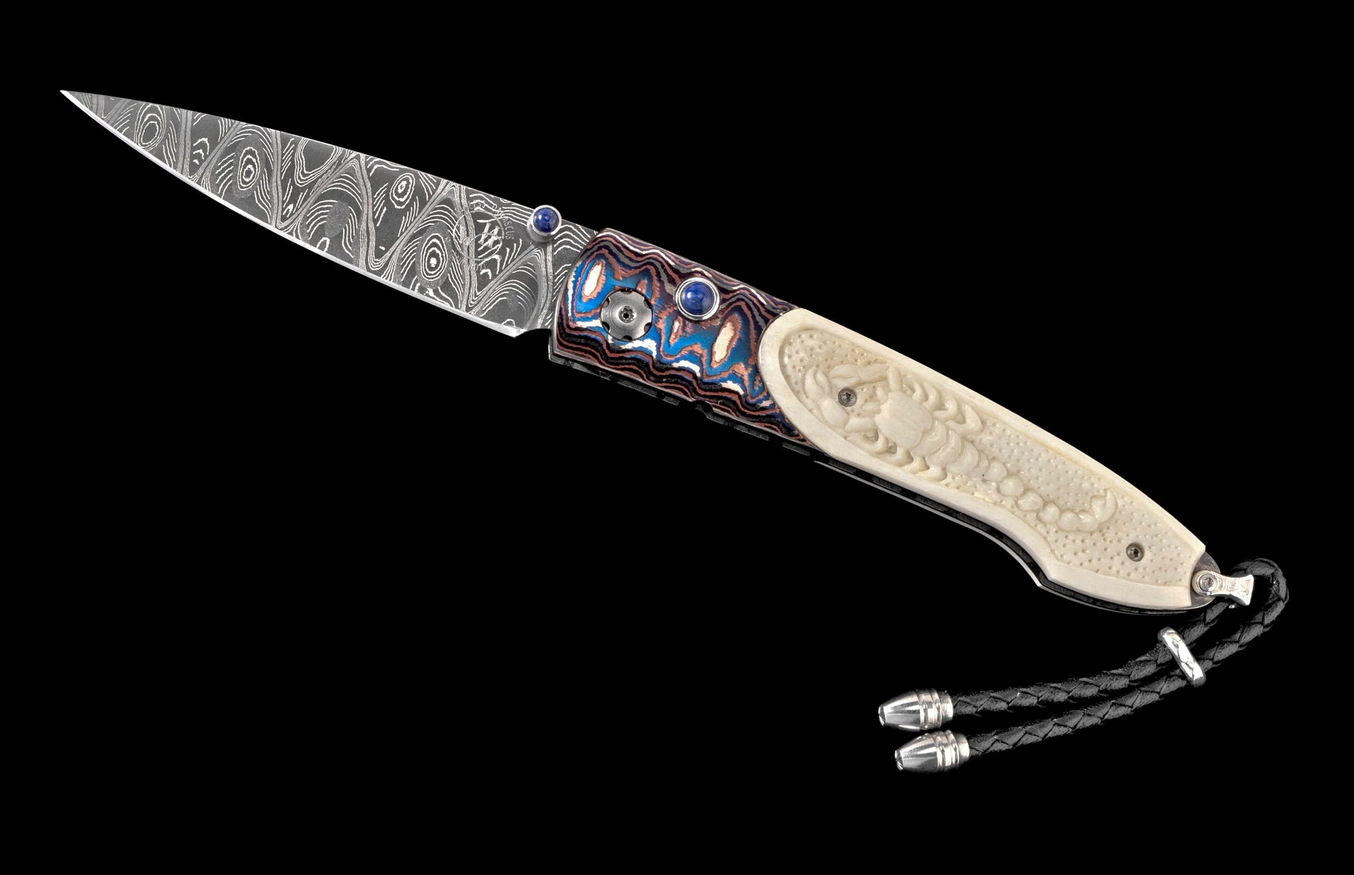 Folding knife with a patterned Damascus blade, a vibrant swirled handle featuring blue gems, and a carved off-white scorpion handle with a black leather lanyard.