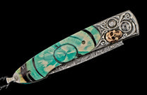 A decorative folding knife with a teal and cream swirled handle, ornate silver metalwork, a gold skull, and a visible Damascus blade.