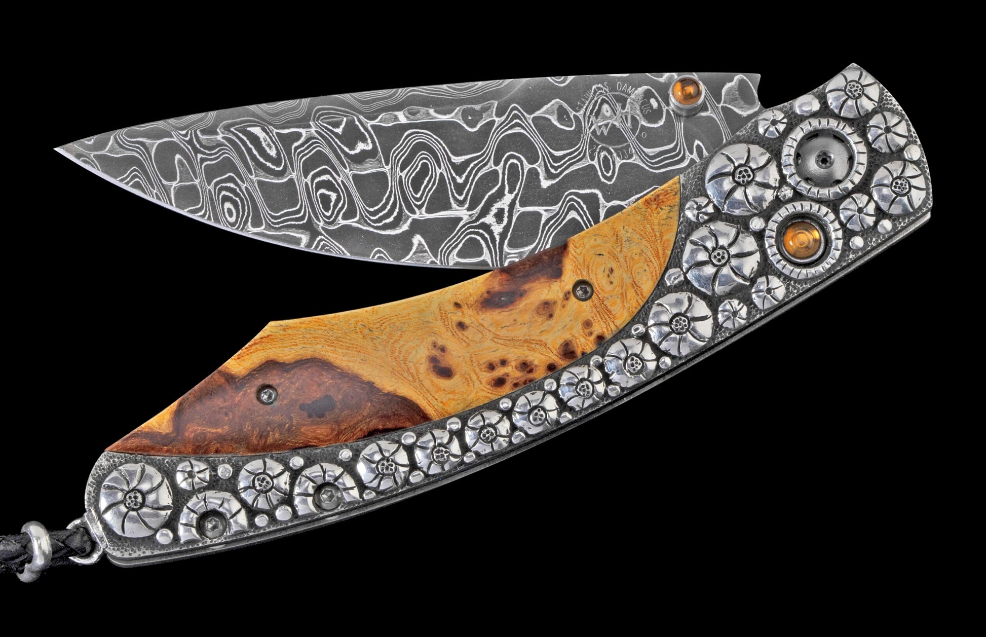 Partially open folding knife with a wavy pattern Damascus steel blade, a two-toned burled wood handle, and intricate silver floral embellishments featuring orange stones.