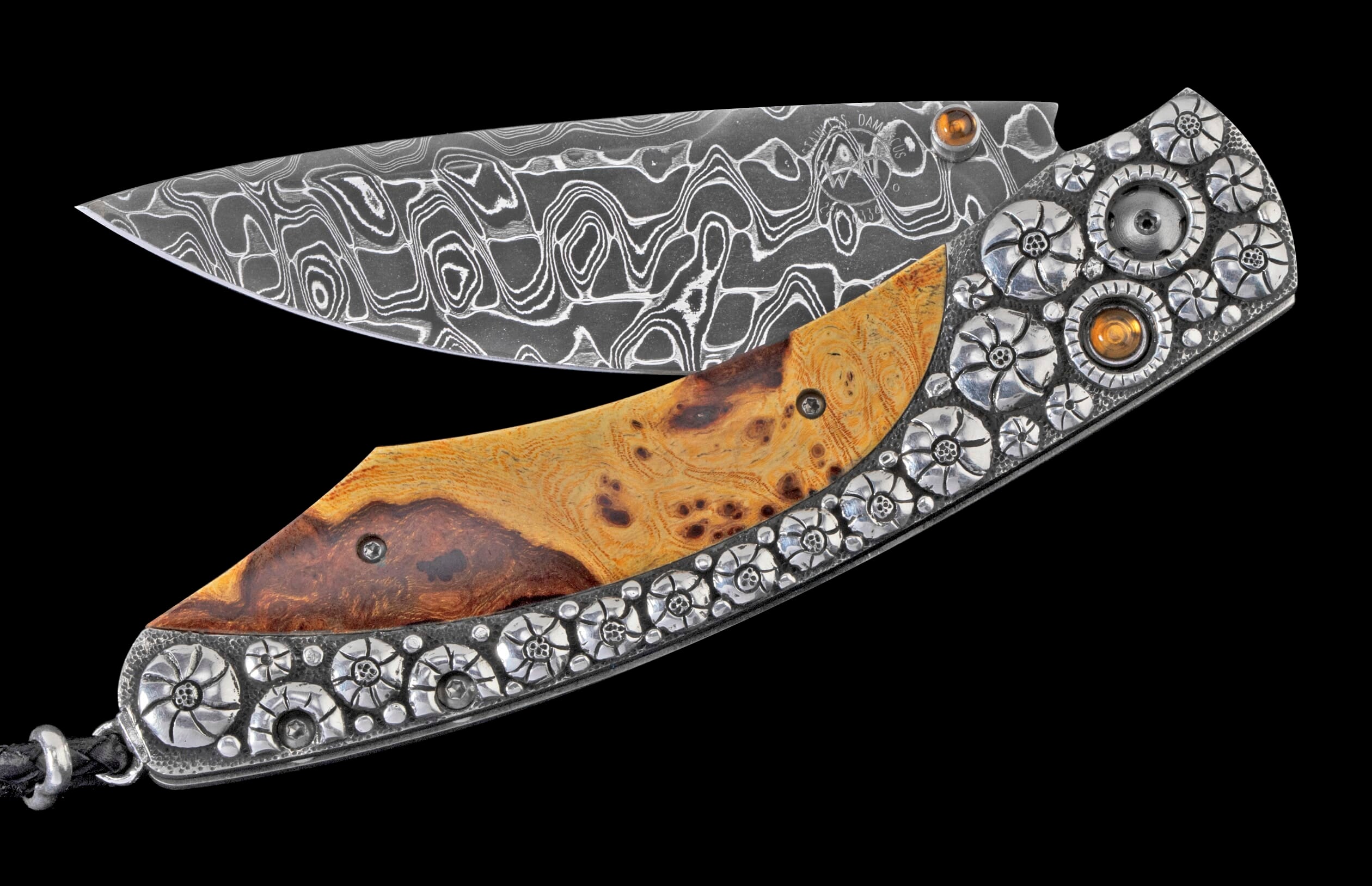 Partially open folding knife with a wavy pattern Damascus steel blade, a two-toned burled wood handle, and intricate silver floral embellishments featuring orange stones.