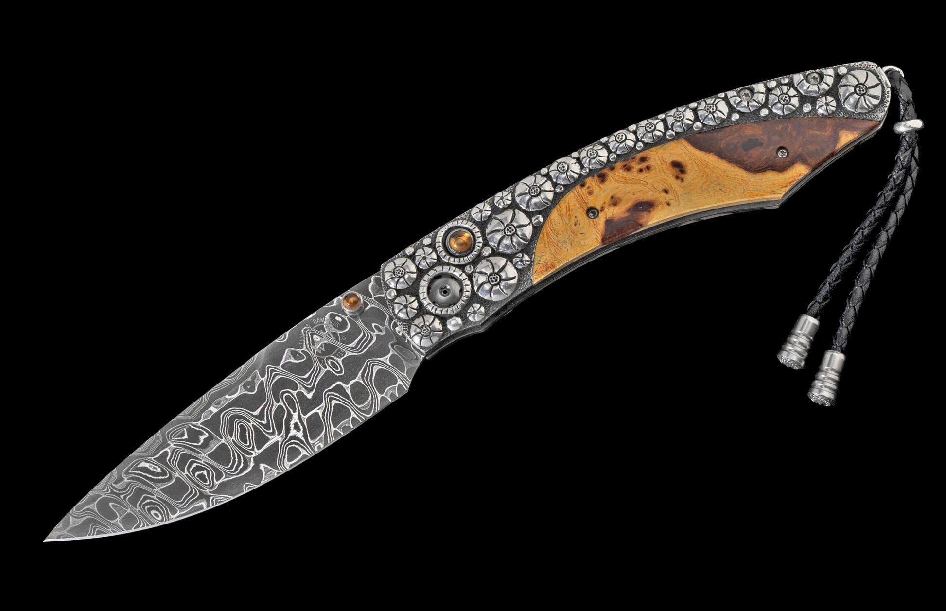 Custom folding knife with a Damascus steel blade, ornate silver-tone handle with floral engraving, burl wood scales, golden gemstones, and a braided leather lanyard.