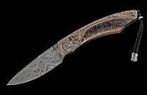 Custom folding knife with swirling Damascus steel blade, textured silver and copper handle with gemstones and antler, and a black leather lanyard.