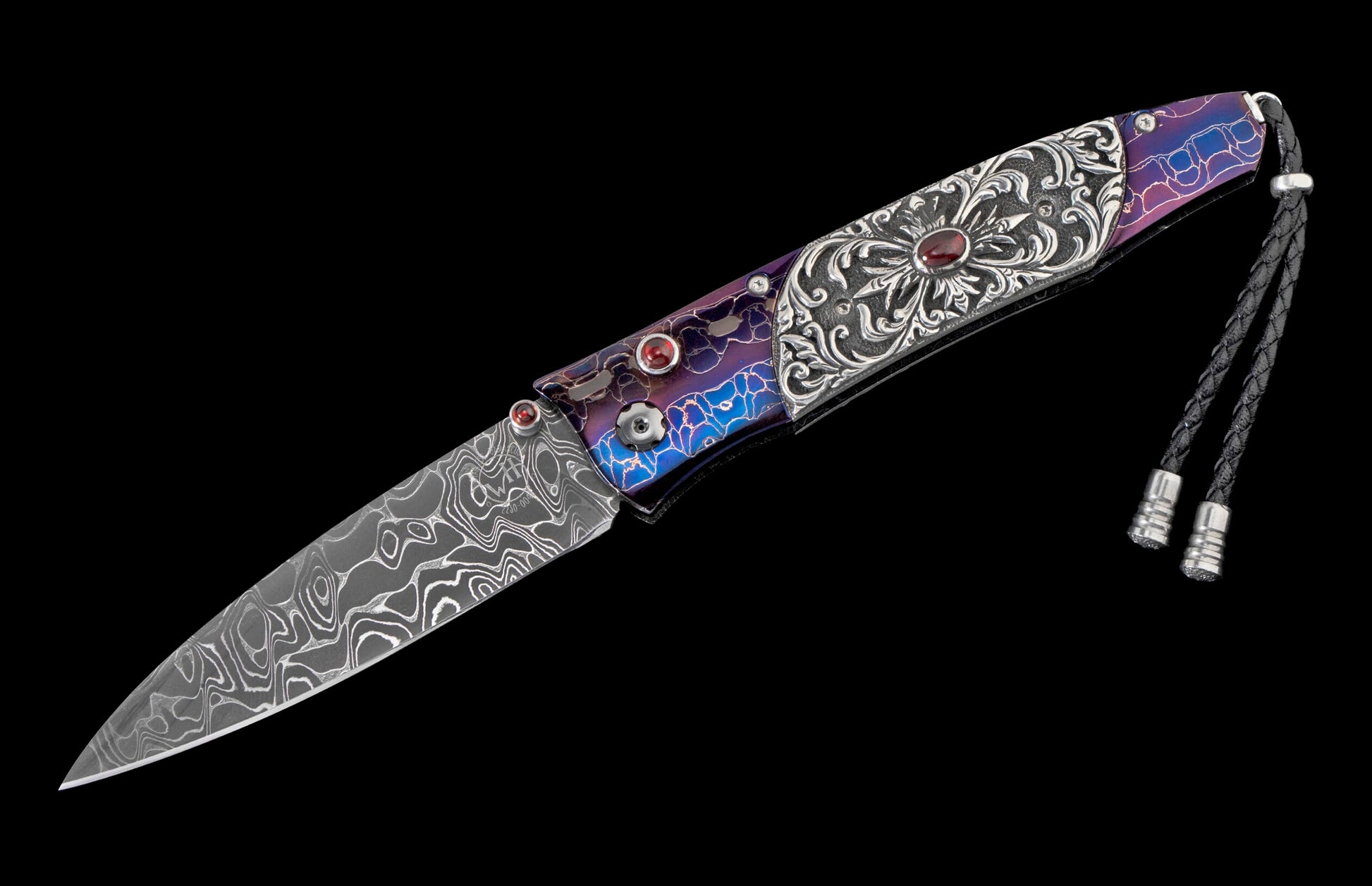 Ornate folding knife with a patterned Damascus steel blade, an engraved silver handle featuring a central red gem, iridescent blue and purple accents, and a black leather lanyard.