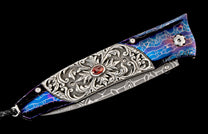 Folding knife with iridescent blue and purple cracked handle scales, ornate silver inlay with a red gemstone, and Damascus steel blade.