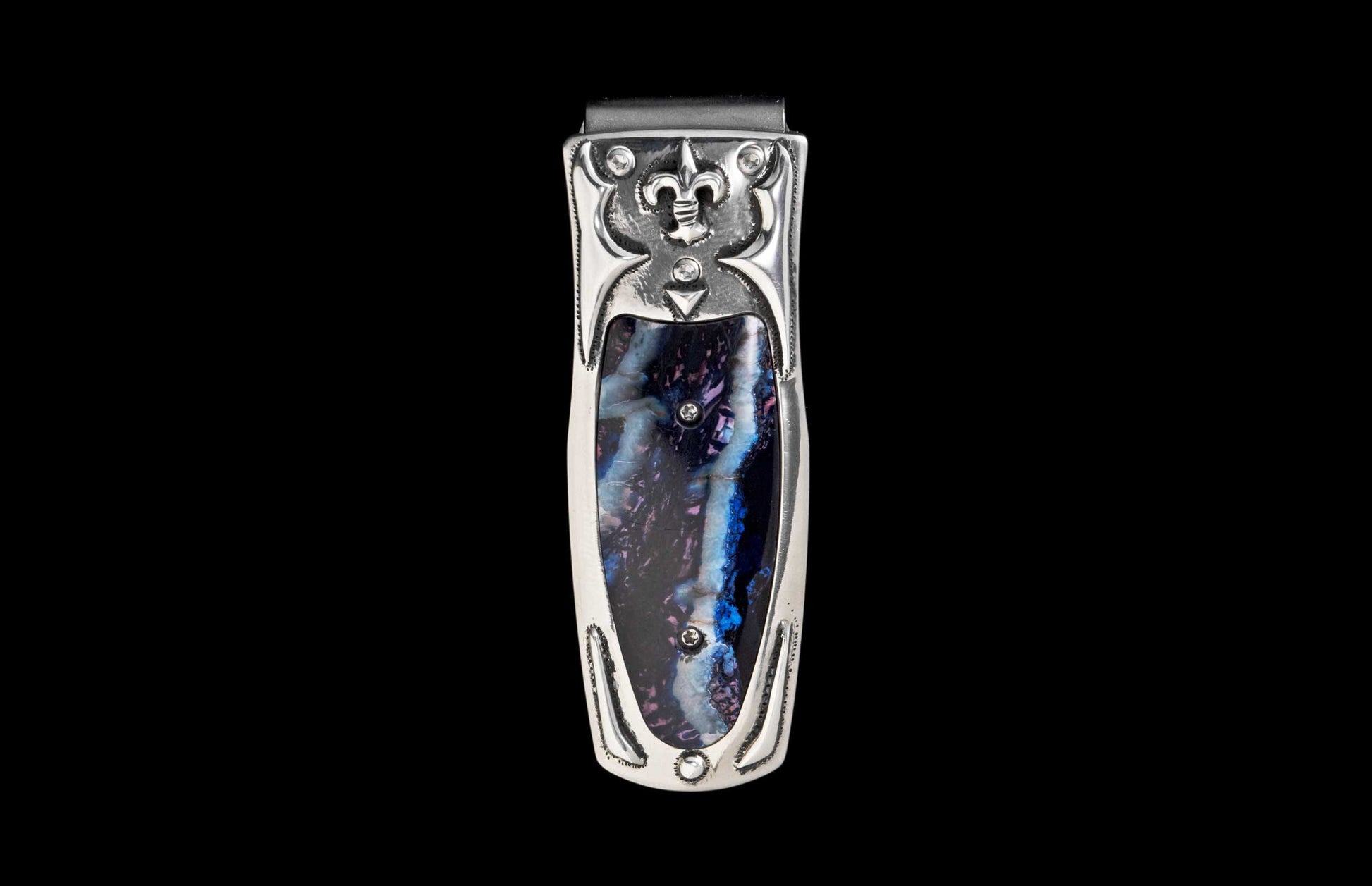 Silver-toned money clip with a blue and purple marbled inlay, featuring a fleur-de-lis, scrollwork, and studded accents.