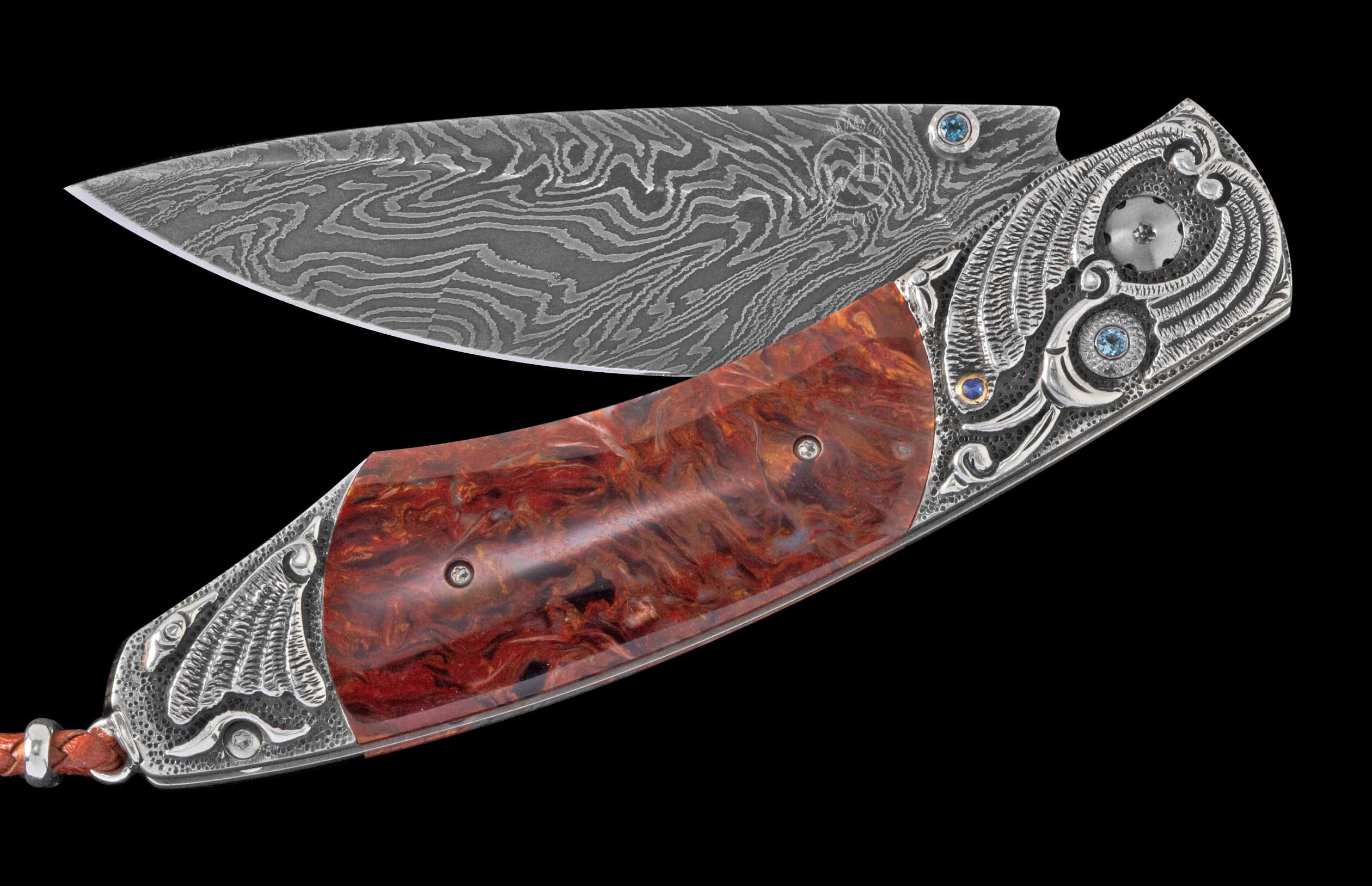 Folding knife with a patterned Damascus steel blade, reddish-brown marbled handle, and intricately engraved silver bolsters with blue gemstones.