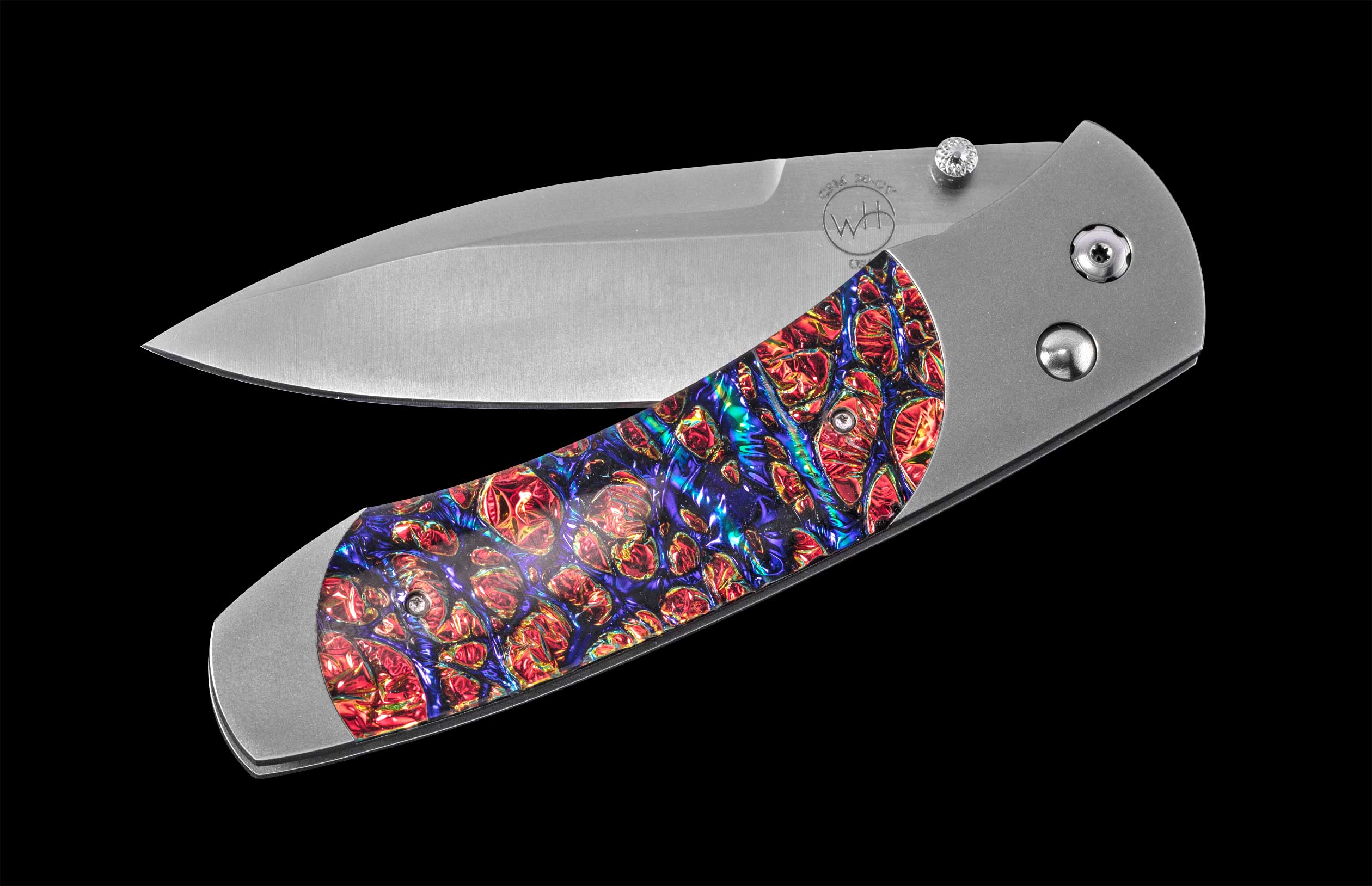 Stainless steel folding knife with vibrant red and blue mokume-gane handle, by WH, featuring a polished blade and textured scales, side view on black background