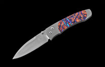 Stainless steel folding knife with vibrant red and blue mokume-gane handle, side view on black background